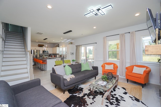 living area with light wood-type flooring, visible vents, recessed lighting, and stairs