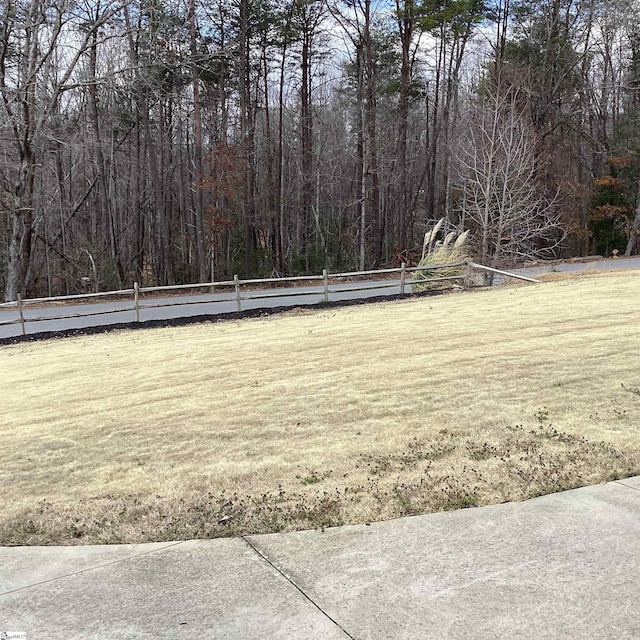 view of yard featuring fence and a wooded view