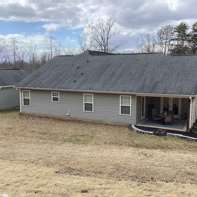 rear view of property with roof with shingles and a patio area