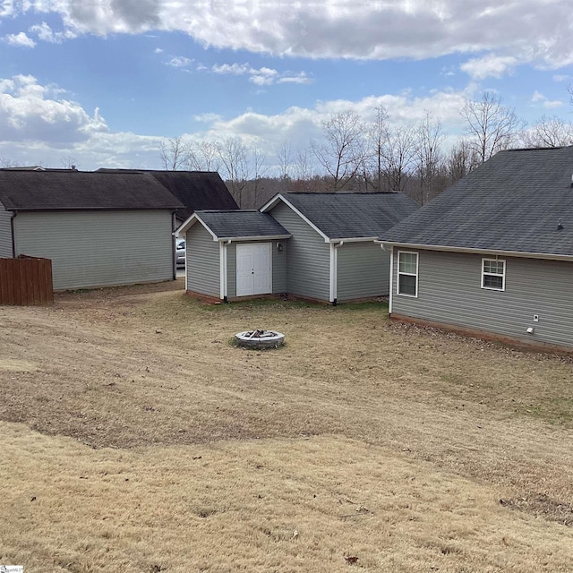 exterior space featuring an outdoor fire pit and roof with shingles