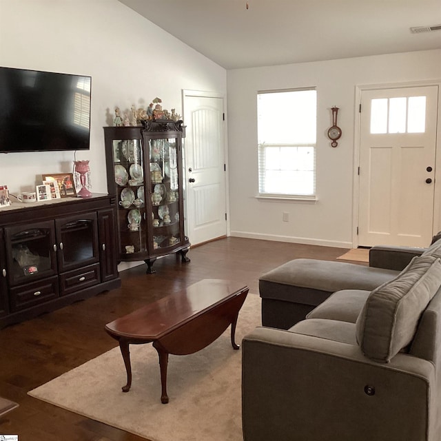 living area featuring lofted ceiling, wood finished floors, visible vents, and baseboards