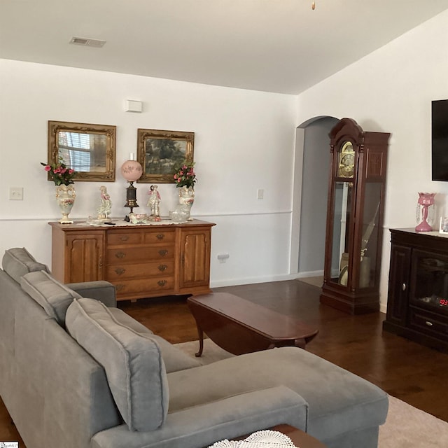 living room featuring visible vents, arched walkways, and dark wood finished floors