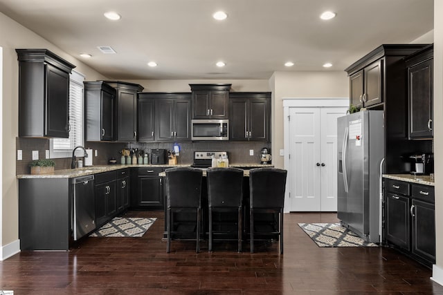 kitchen with appliances with stainless steel finishes, dark wood-type flooring, a sink, and visible vents