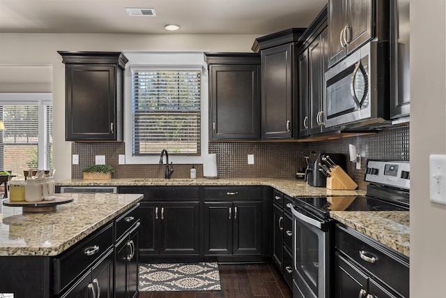 kitchen featuring visible vents, decorative backsplash, dark wood-type flooring, stainless steel appliances, and a sink