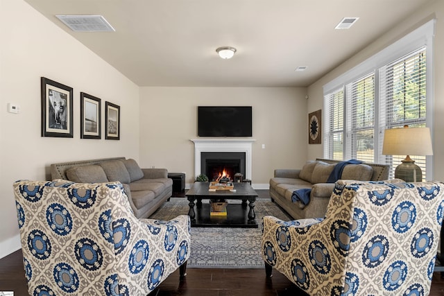 living room with dark wood-style floors, a lit fireplace, and visible vents