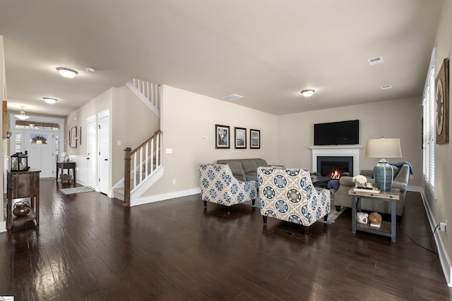 living room featuring visible vents, stairway, wood finished floors, and a lit fireplace