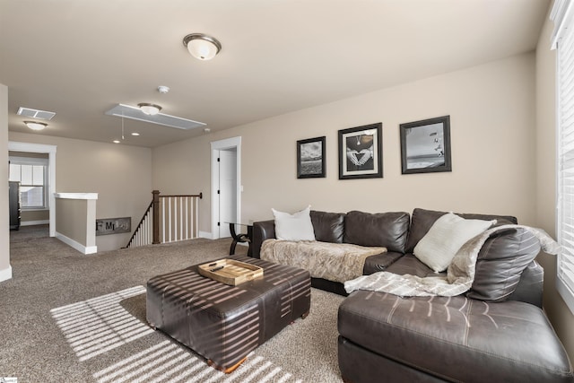 carpeted living area featuring attic access, visible vents, and baseboards