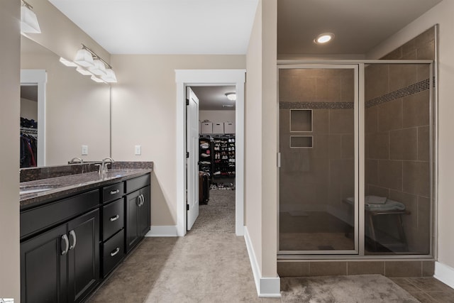 bathroom featuring baseboards, double vanity, a sink, and a shower stall