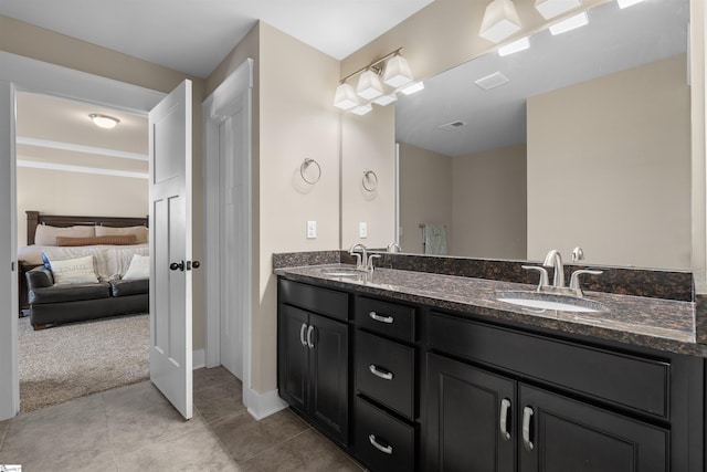 ensuite bathroom with double vanity, visible vents, a sink, and tile patterned floors