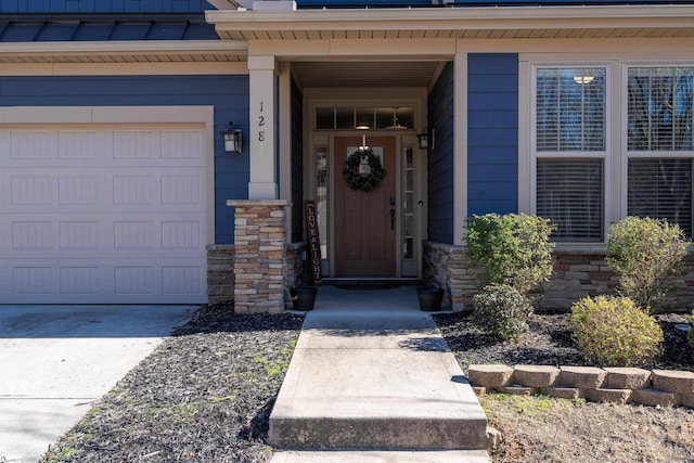 doorway to property featuring stone siding, metal roof, an attached garage, and a standing seam roof