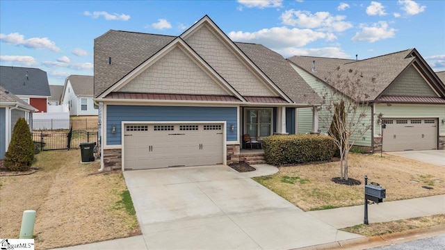 craftsman-style home featuring concrete driveway, a standing seam roof, fence, a garage, and stone siding