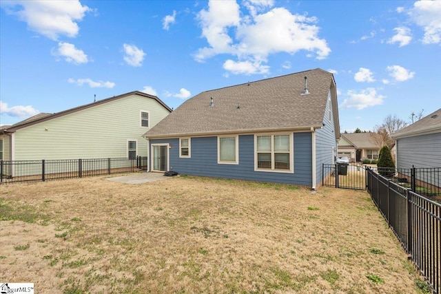 rear view of house featuring a patio, a shingled roof, a lawn, and a fenced backyard