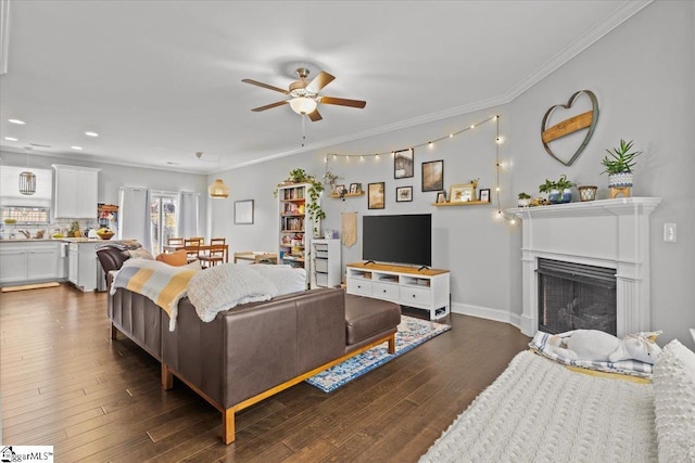 living room featuring ceiling fan, ornamental molding, a fireplace, and dark wood finished floors