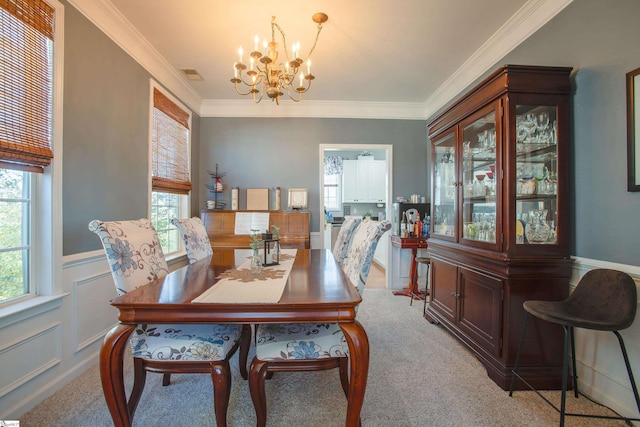 dining room with a wainscoted wall, a notable chandelier, visible vents, a decorative wall, and ornamental molding