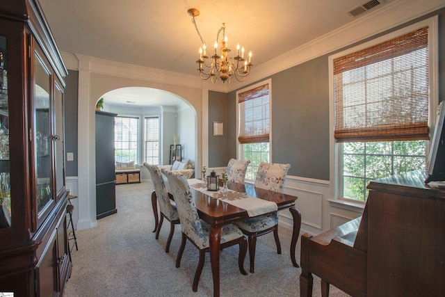 dining area featuring visible vents, arched walkways, wainscoting, light colored carpet, and an inviting chandelier