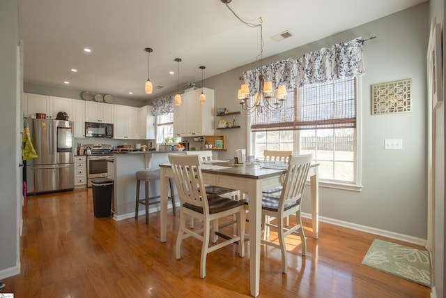 dining room featuring light wood-type flooring, plenty of natural light, and baseboards