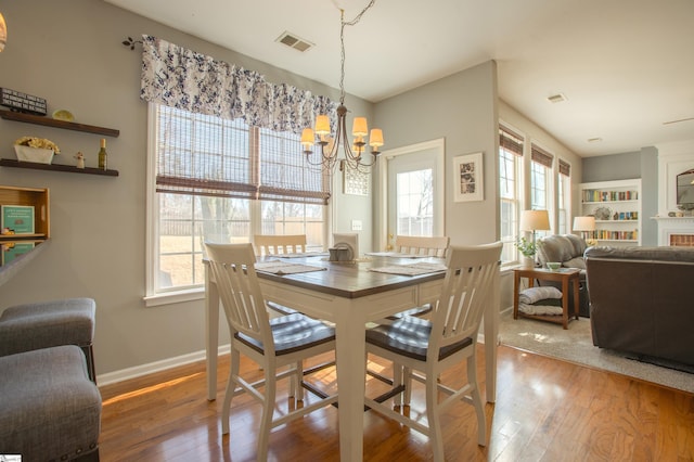 dining space featuring plenty of natural light, wood-type flooring, visible vents, and a notable chandelier