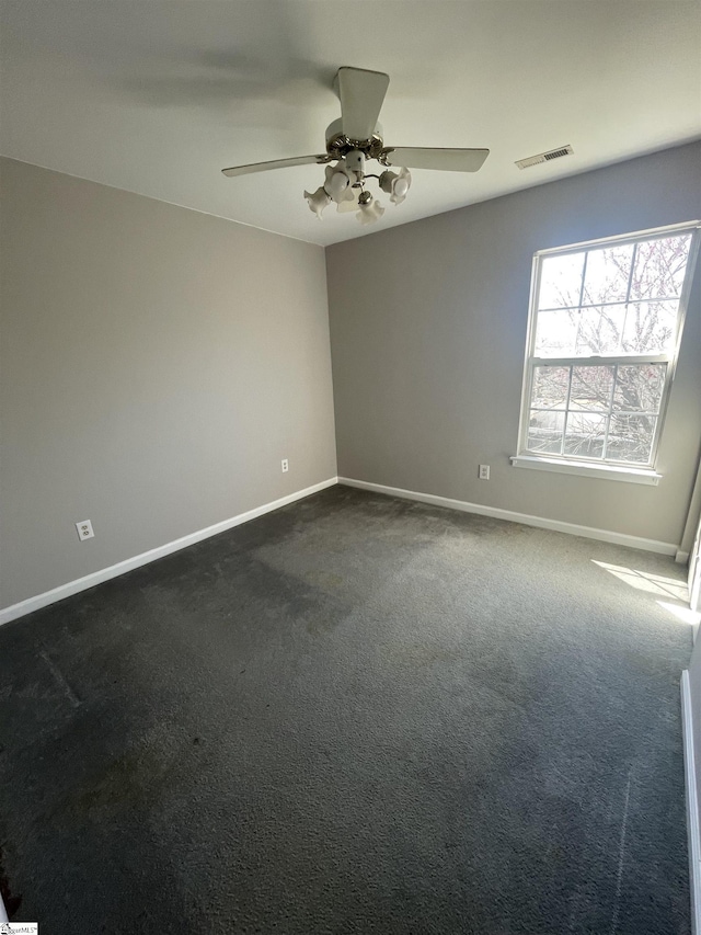 spare room with ceiling fan, baseboards, visible vents, and dark colored carpet