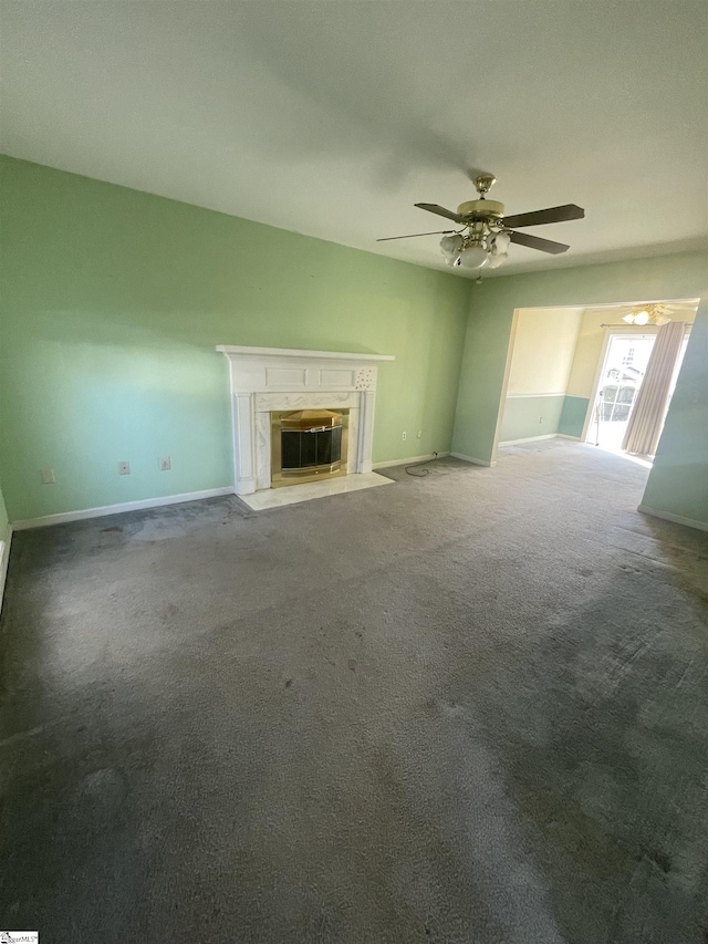 unfurnished living room featuring a ceiling fan, carpet flooring, baseboards, and a premium fireplace