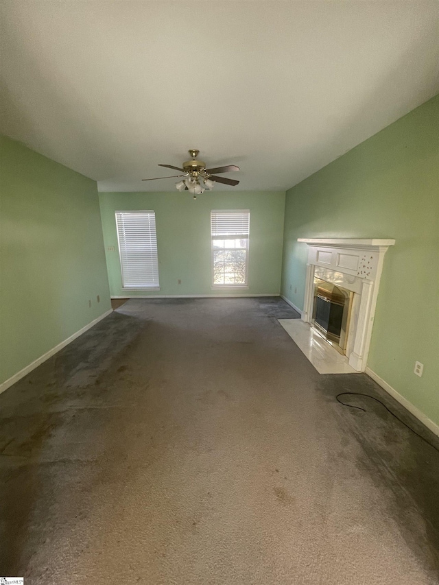 unfurnished living room featuring carpet, ceiling fan, baseboards, and a premium fireplace