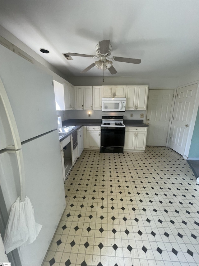 kitchen featuring white appliances, a ceiling fan, dark countertops, cream cabinetry, and light floors