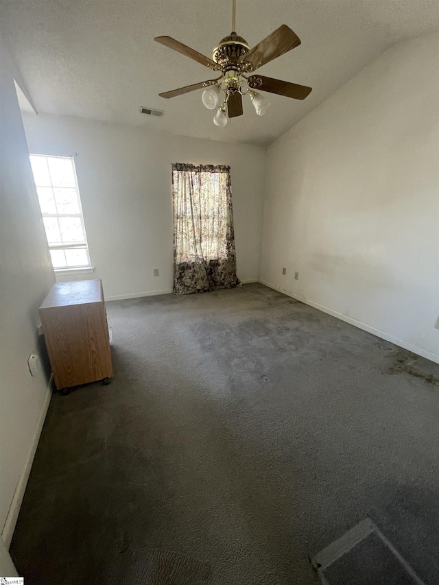 carpeted empty room with plenty of natural light, visible vents, vaulted ceiling, and baseboards