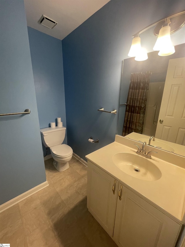 bathroom with baseboards, visible vents, vanity, and toilet