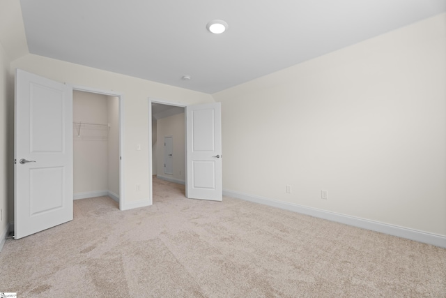 unfurnished bedroom featuring light colored carpet, baseboards, and a closet