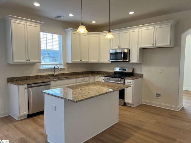 kitchen featuring arched walkways, visible vents, stainless steel appliances, white cabinetry, and a sink