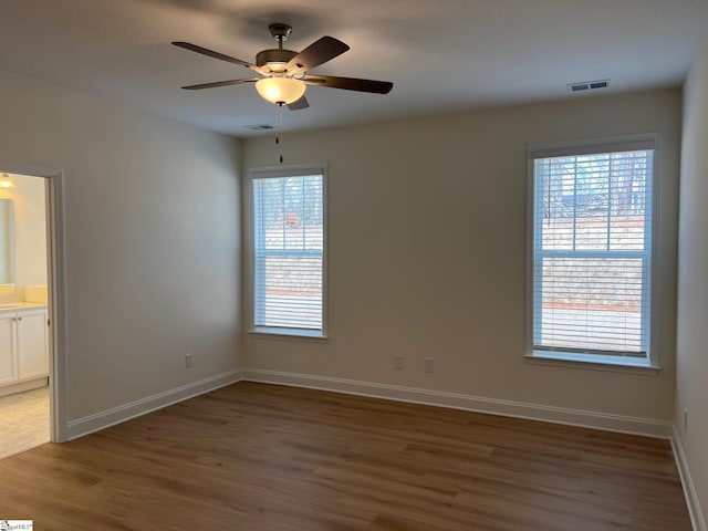 empty room with visible vents, ceiling fan, baseboards, and wood finished floors