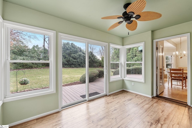 unfurnished sunroom featuring ceiling fan with notable chandelier