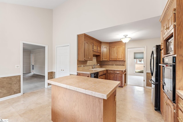 kitchen featuring decorative backsplash, light carpet, a sink, and black appliances