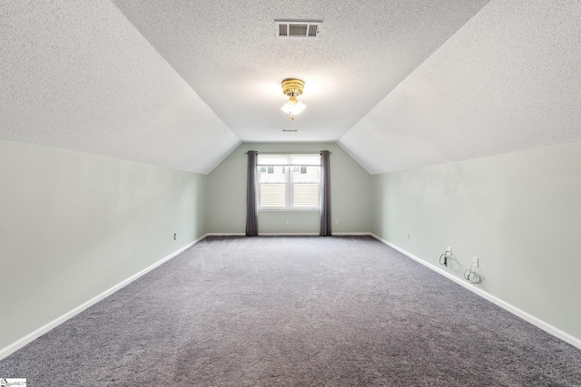 additional living space with carpet floors, lofted ceiling, visible vents, and baseboards