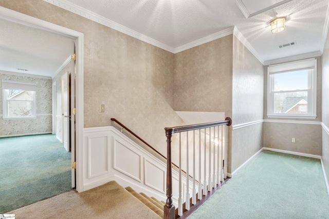 stairway featuring a wainscoted wall, carpet flooring, visible vents, ornamental molding, and wallpapered walls