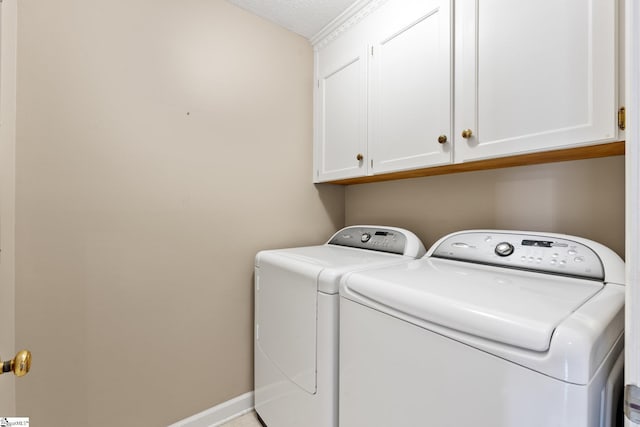 washroom with cabinet space, a textured ceiling, baseboards, and washer and dryer