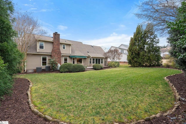 back of property featuring cooling unit, a yard, and a chimney