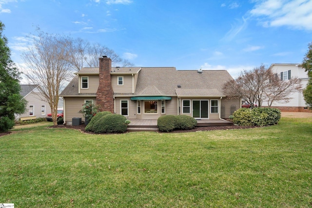 rear view of house featuring a deck, central air condition unit, roof with shingles, a lawn, and a chimney