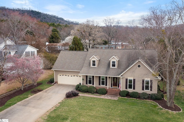 cape cod home featuring a garage, a shingled roof, concrete driveway, covered porch, and a front lawn