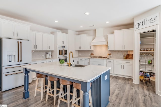 kitchen with white appliances, white cabinetry, a sink, and custom exhaust hood