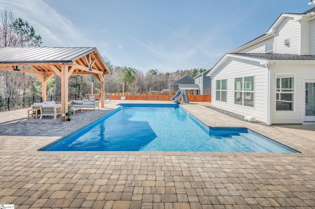 view of swimming pool with a fenced backyard, a water slide, a patio area, outdoor lounge area, and a playground