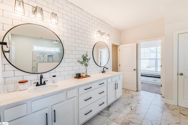 bathroom featuring marble finish floor, double vanity, a sink, and decorative backsplash