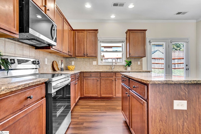 kitchen featuring appliances with stainless steel finishes, a sink, visible vents, and brown cabinets