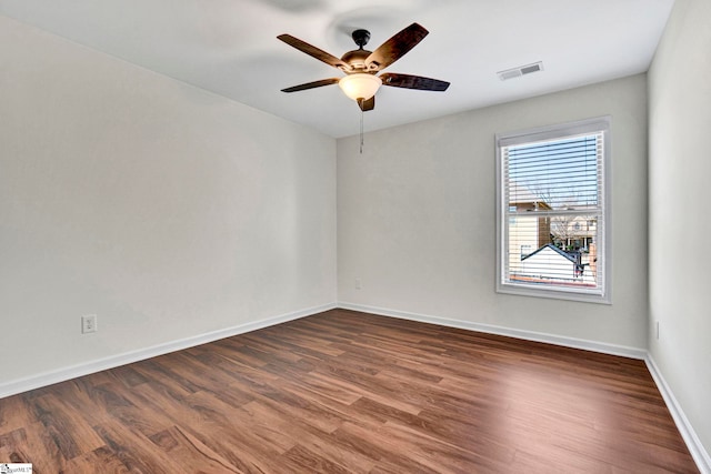 unfurnished room featuring baseboards, visible vents, ceiling fan, and wood finished floors