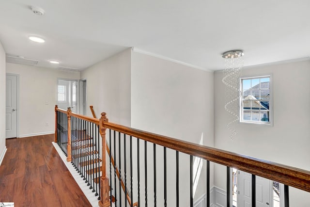 corridor featuring wood finished floors, an upstairs landing, baseboards, attic access, and crown molding