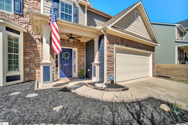 view of front of property with driveway, stone siding, an attached garage, and a ceiling fan