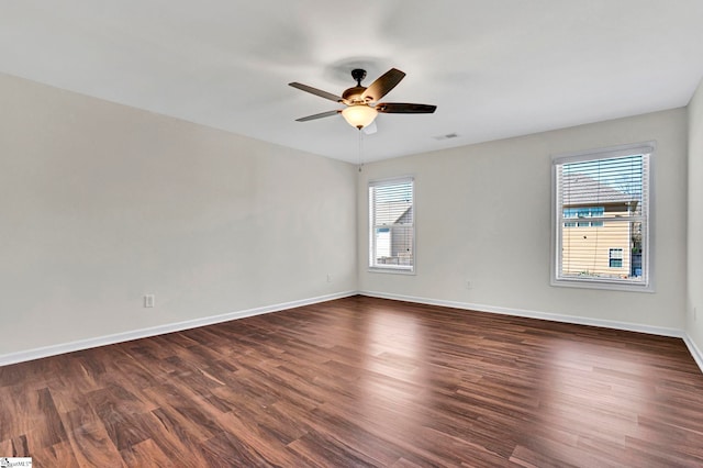 empty room with dark wood-style floors, visible vents, baseboards, and a ceiling fan