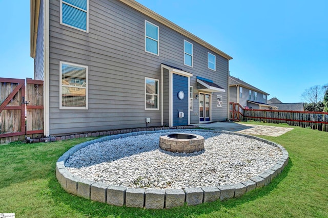 back of property featuring a fire pit, a patio area, fence, and a lawn