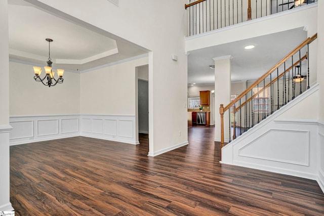 foyer with stairs, a chandelier, dark wood finished floors, and crown molding