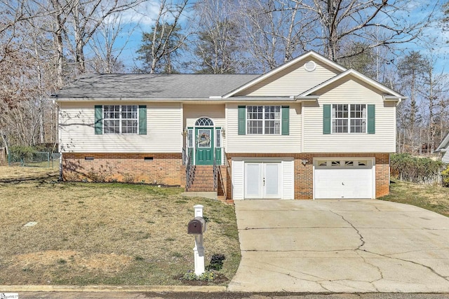 bi-level home featuring a garage, driveway, brick siding, and a front yard