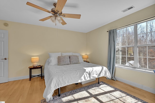 bedroom featuring a ceiling fan, baseboards, visible vents, and light wood finished floors